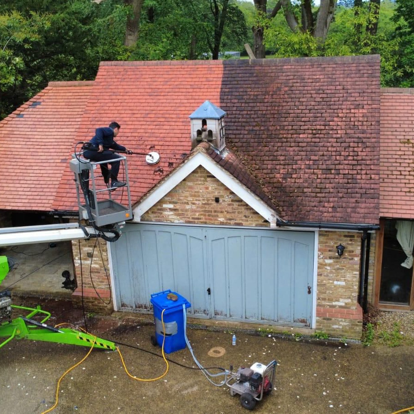 Softwash roof cleaning in progress from a powered access platform